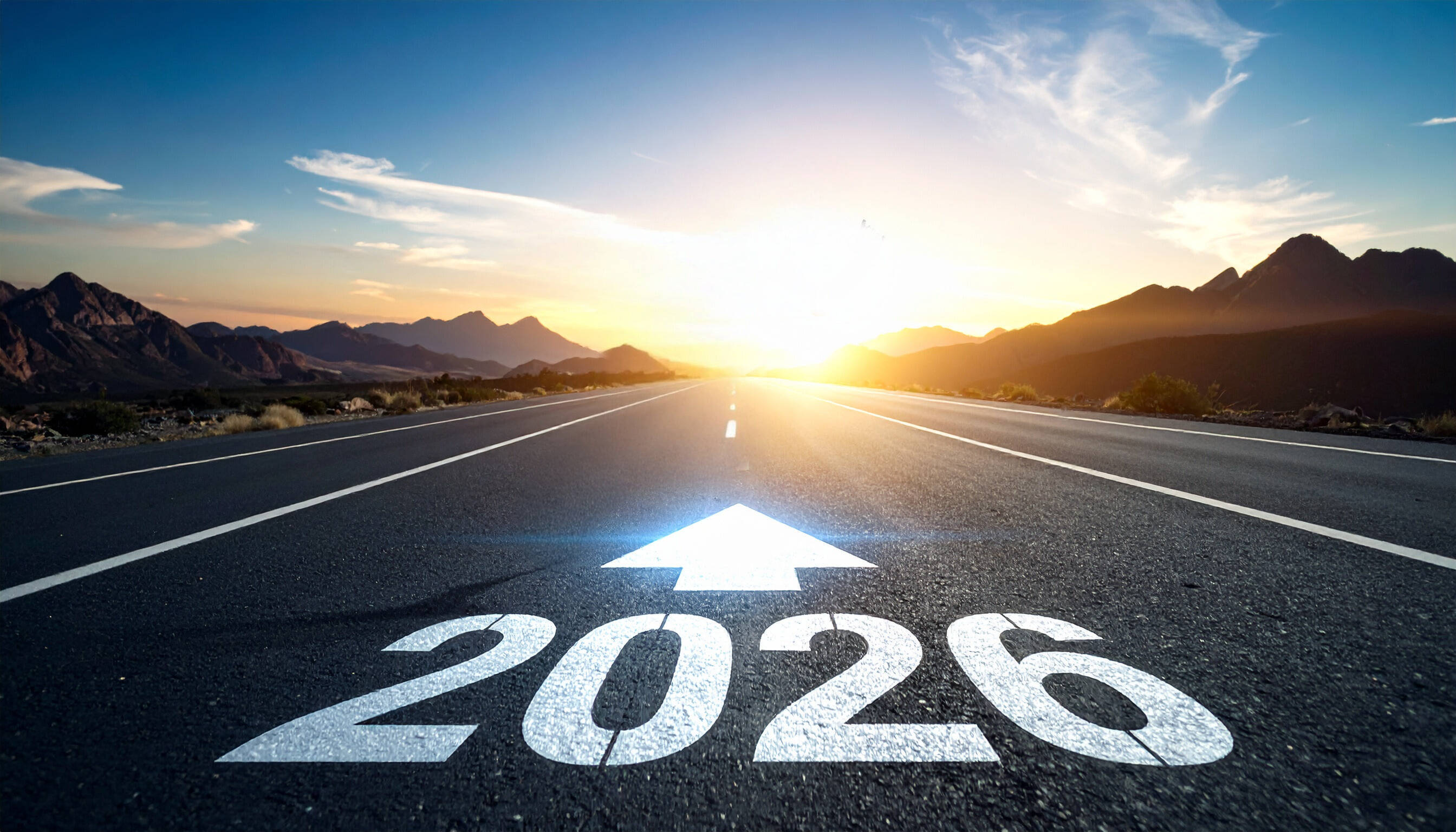 Looking ahead to 2026: A road to future vision.  The image features an arrow pointing the road towards 2026 with a beautiful sky and mountains in background.